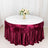Round table with burgundy satin tablecloth and floral centerpiece.