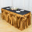 Elegant gold pleated table skirt draped over a black tablecloth with decorative accents.