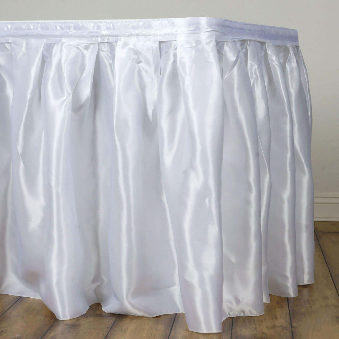 White satin table skirt draping elegantly over the edge of a table.