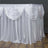 Elegant white table skirt with draped fabric for events and gatherings.