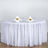 Round table with white tablecloth set for dining with glasses and napkins.