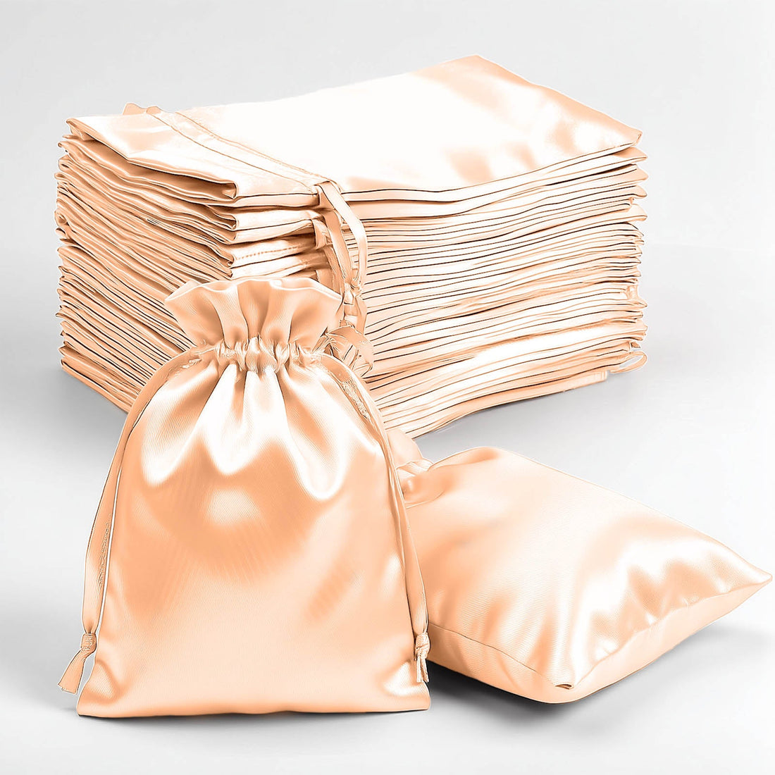 Set of satin drawstring bags in peach color, including one bag in front.