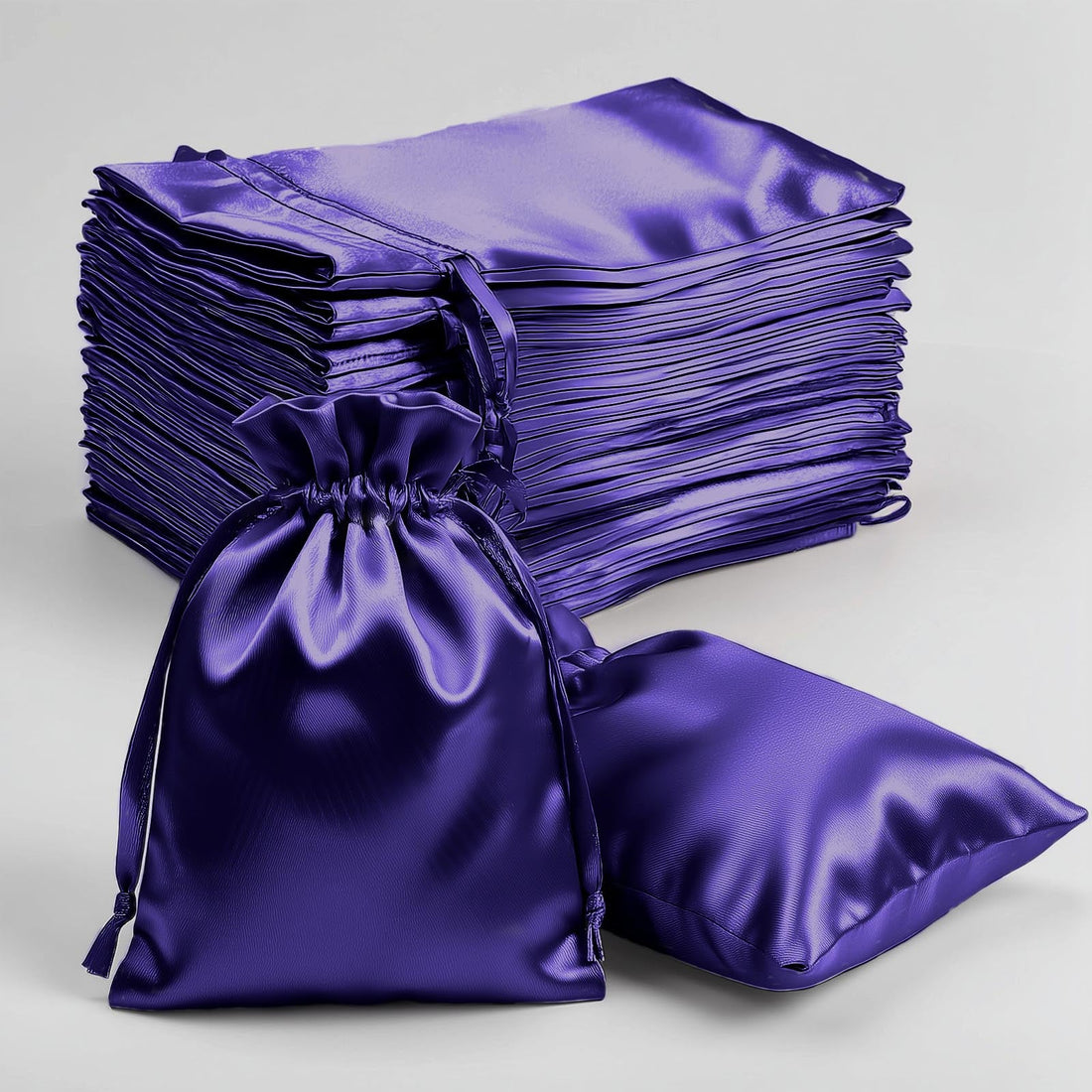 Purple satin drawstring bags stacked with one bag and cushion on the side.