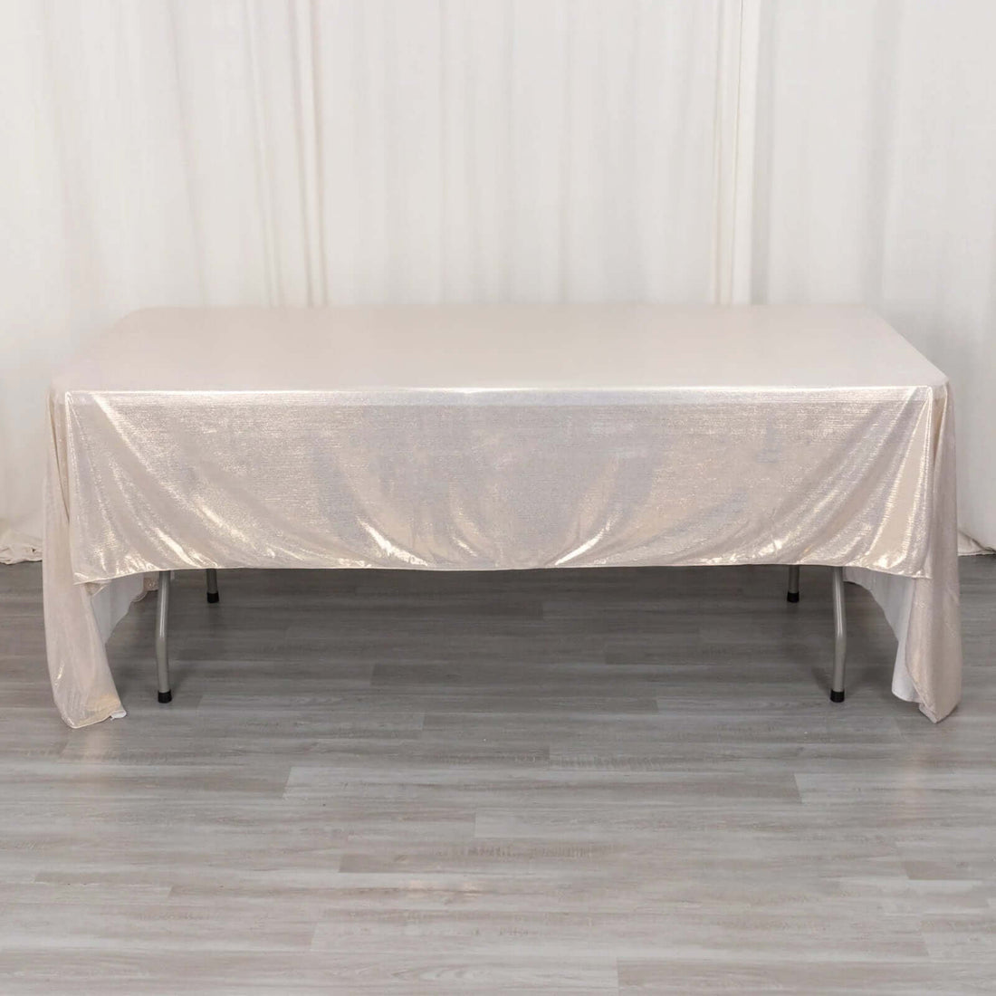 Shiny champagne tablecloth draped over a table in a studio setting