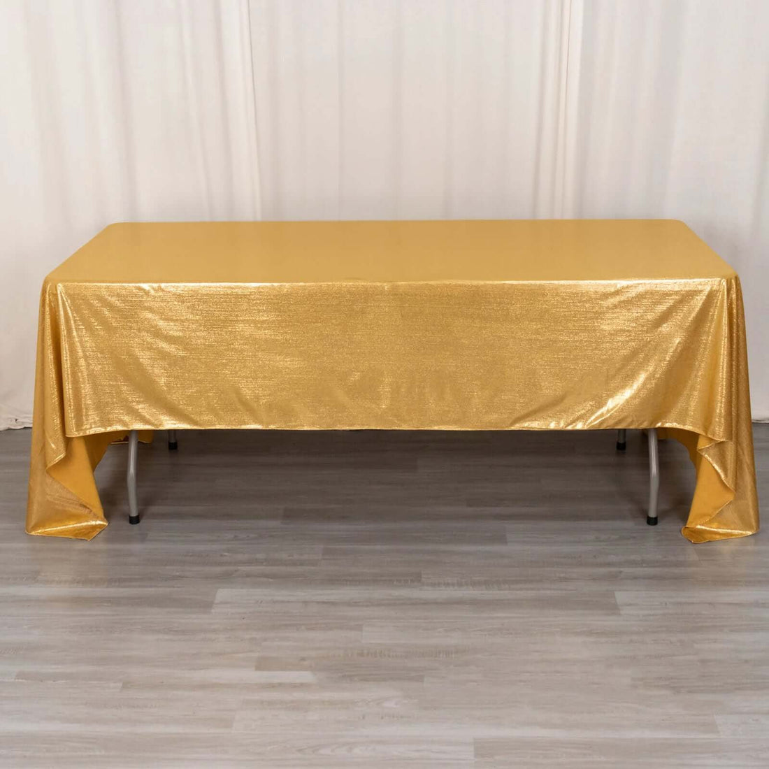 Gold glitter tablecloth draping over a table in a studio setting.