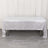 Silver tablecloth draped over a table on a wooden floor.