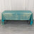 Teal tablecloth draped over a table on a light wooden floor.