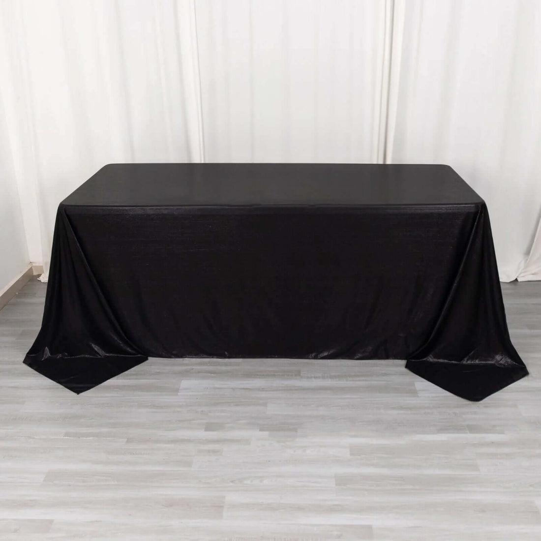 Black table draped with a sleek tablecloth for event styling.