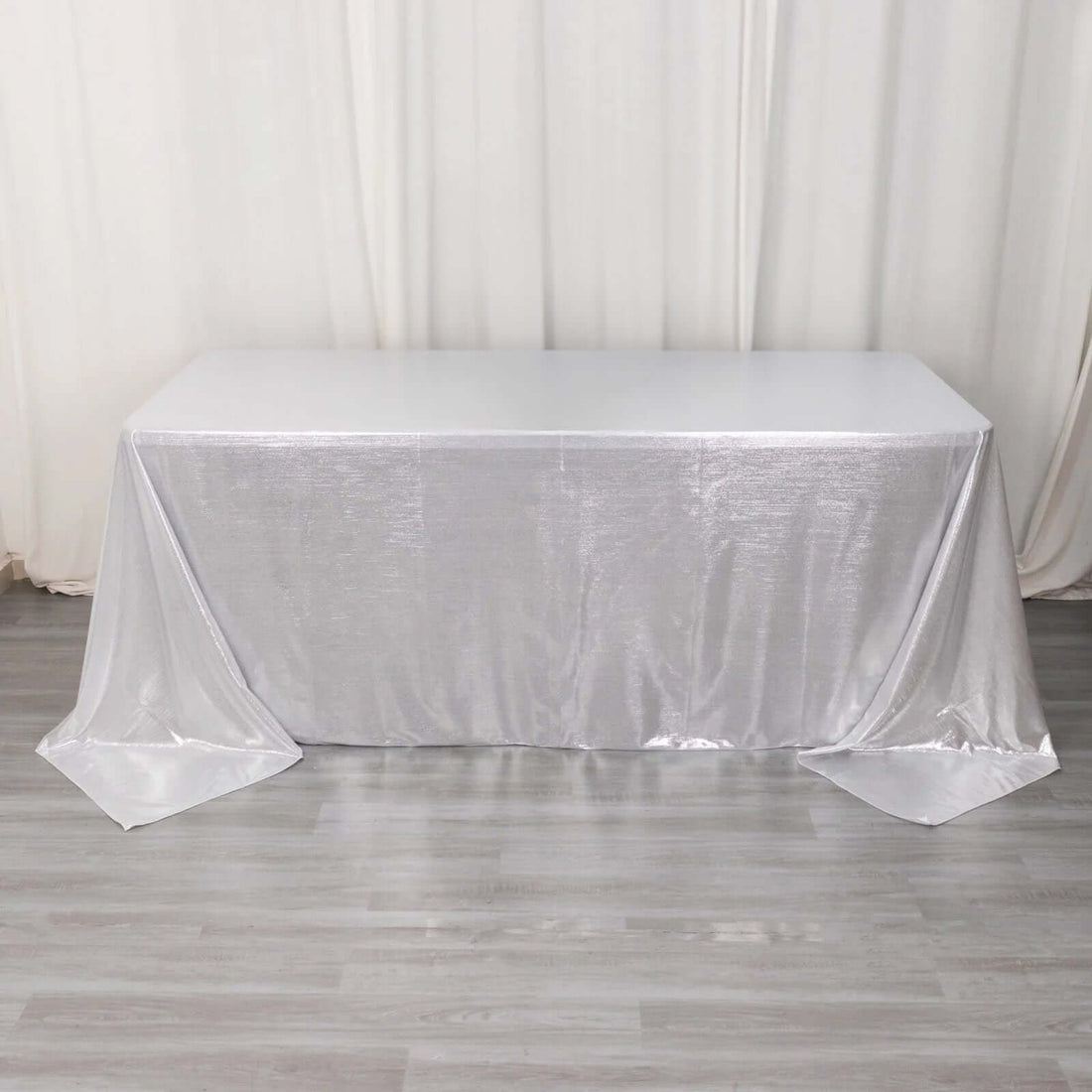 White table with a silver tablecloth draping elegantly.