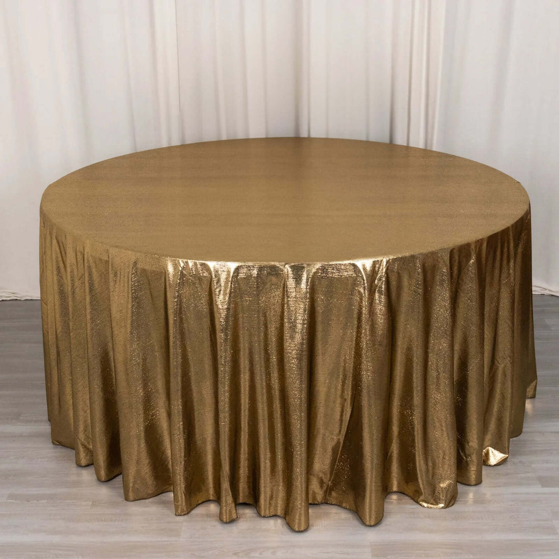 Gold shimmer tablecloth draping a round table in a studio setting.