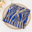 Blue and gold sequin fabric folded on a decorative plate.