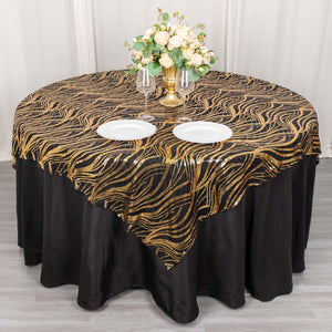 Elegant black and gold tablecloth draped over round table with floral centerpiece.