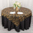 Elegant black and gold tablecloth draped over round table with floral centerpiece.