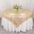 Gold patterned tablecloth with floral centerpiece on round table.