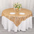 Gold lace tablecloth draped over a round table with floral centerpiece and glassware.