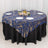 Elegant blue and gold patterned tablecloth on a round table with white plates.