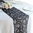 Black lace table runner with floral design on a dining table setting.