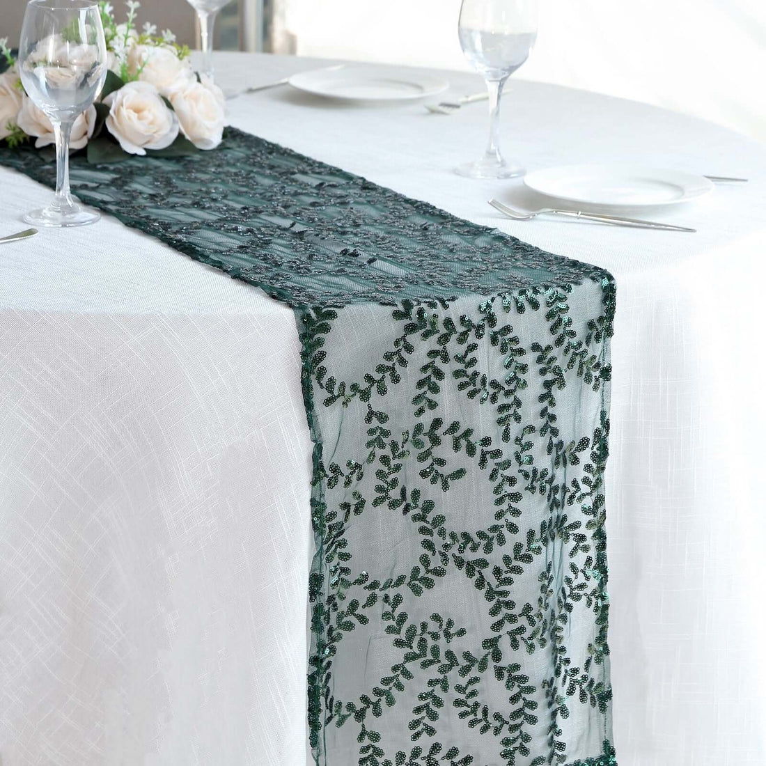 Embroidered green table runner on a white tablecloth with floral decor.
