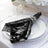 Black sequin napkin elegantly draped on a white plate with a decorative ring.