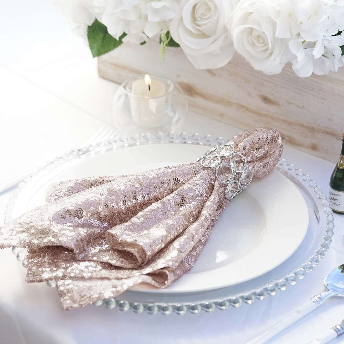 Elegant sequin napkin with a jeweled ring on a beautifully set dinner plate.