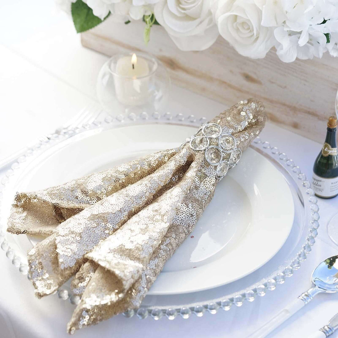 Elegant gold sequin napkin with crystal holder on a white plate.