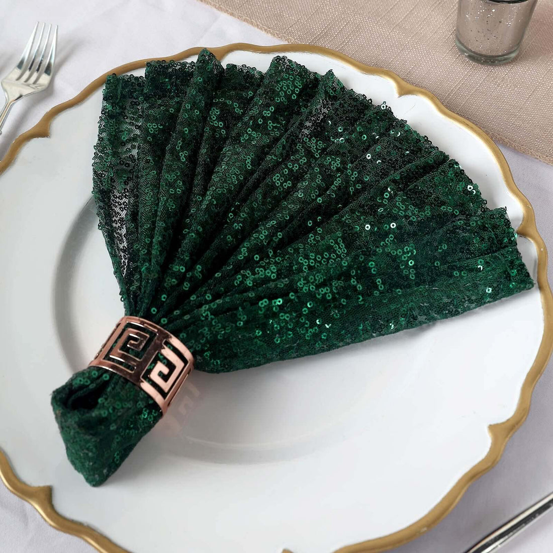 Green sequin napkin elegantly folded on a decorative plate.