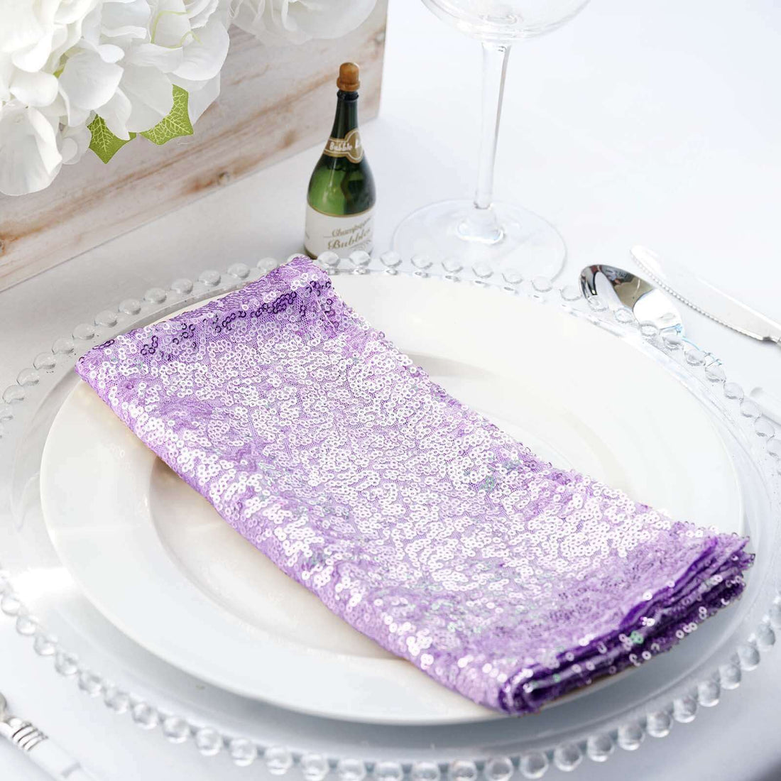 Purple sequin napkin elegantly placed on a white plate with decorative glassware.