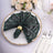 Elegant green sequined napkin on a decorative plate with floral centerpiece.
