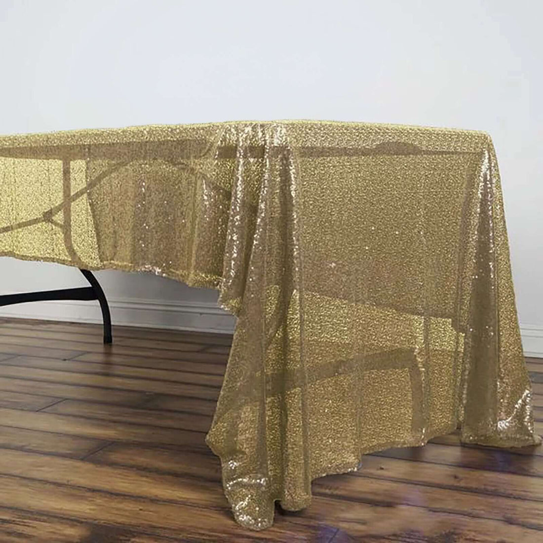 Gold sequin tablecloth draped over a table, shimmering in light.