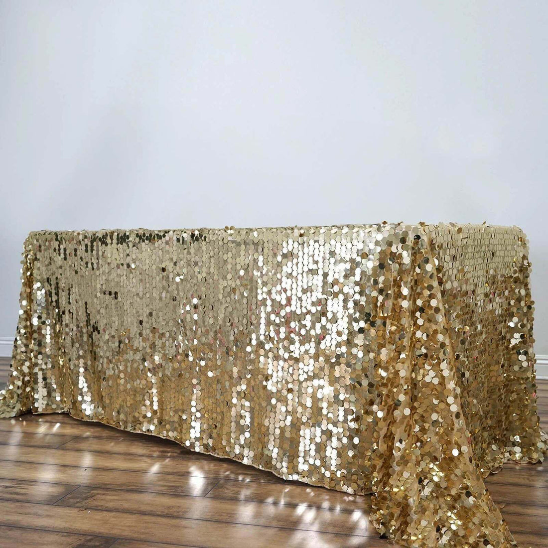 Gold sequin tablecloth draped elegantly on a wooden table.