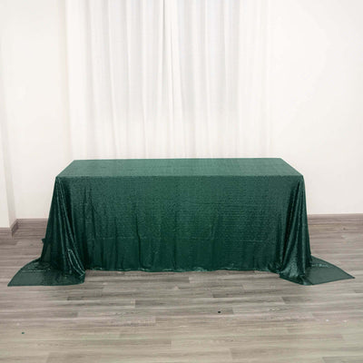 Green sequined tablecloth draped over a table in a studio setting.