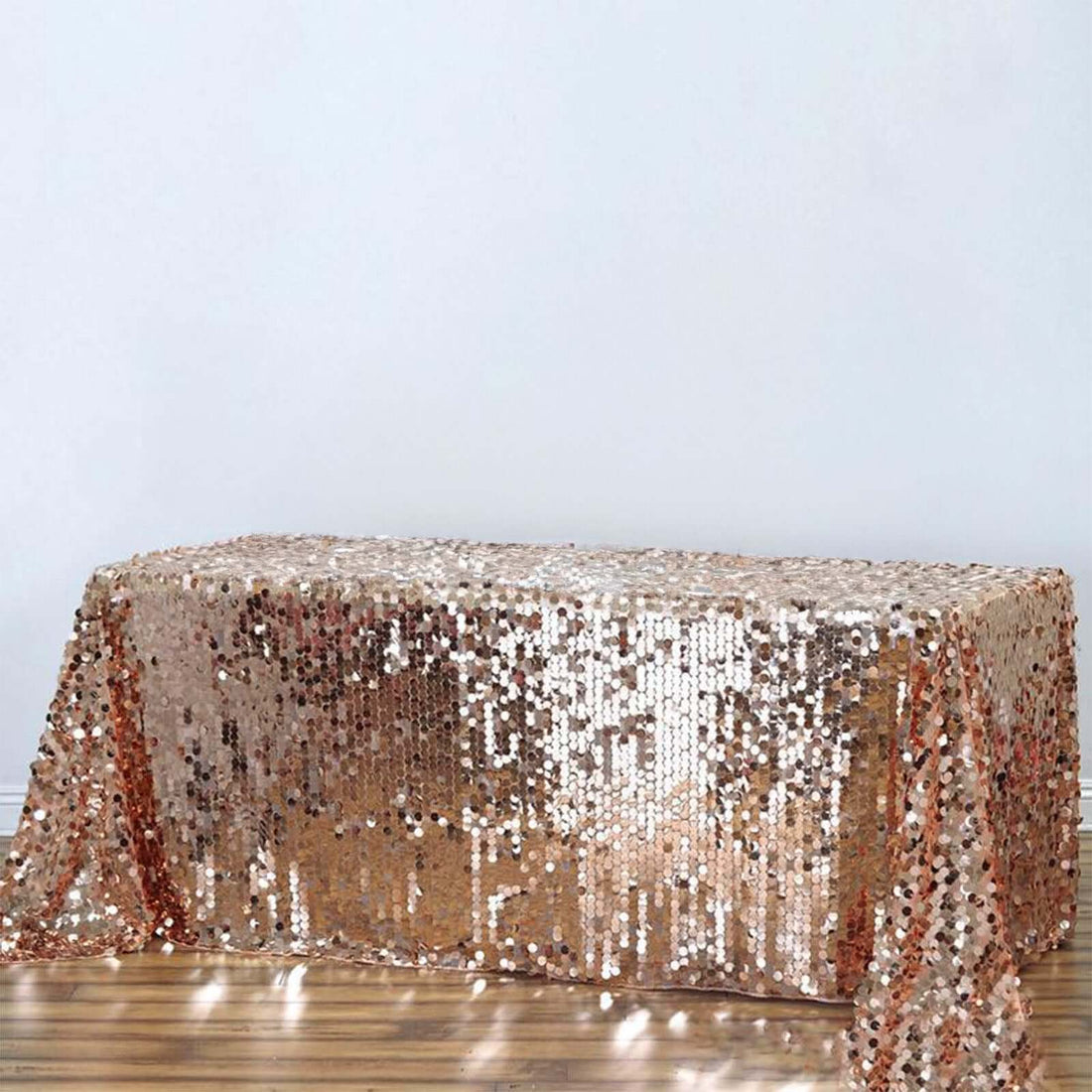 Rose gold sequin table cover on a plain backdrop.