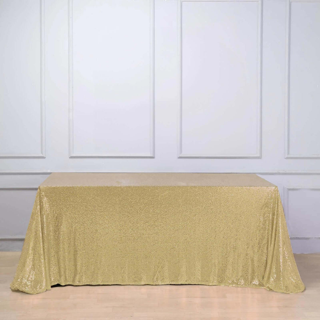 Gold sequin tablecloth draped over a table in a studio setting.
