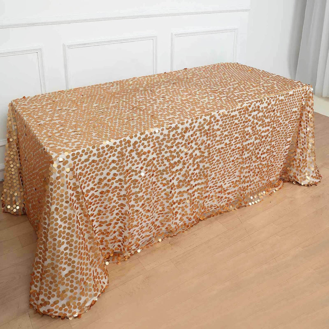 Gold dotted sequin tablecloth draped over a table in a bright setting.