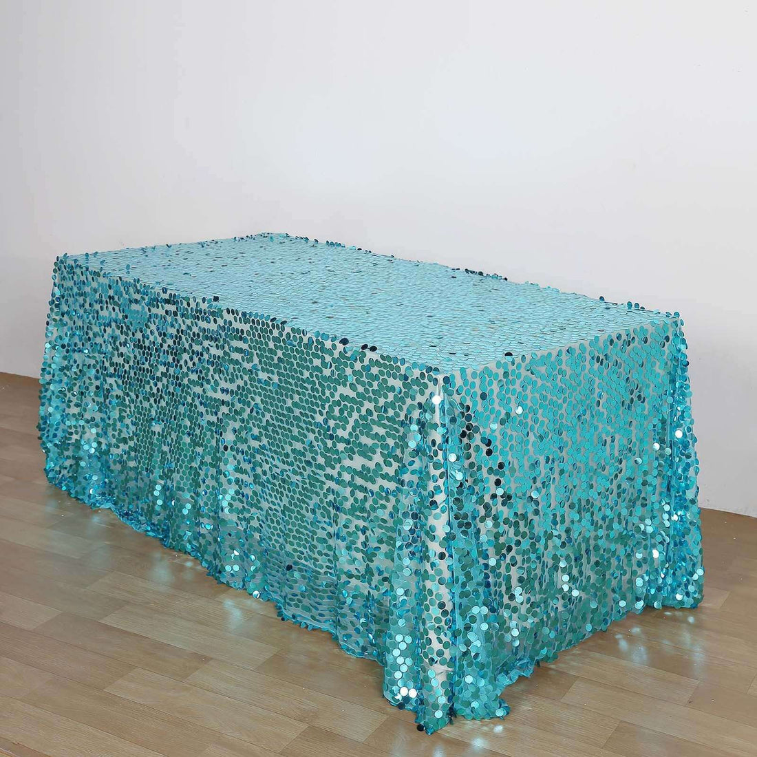 Blue sequin tablecloth on floor against white wall