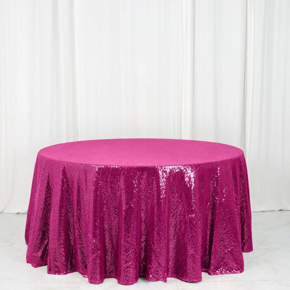 Round fuchsia sequin tablecloth on a white backdrop
