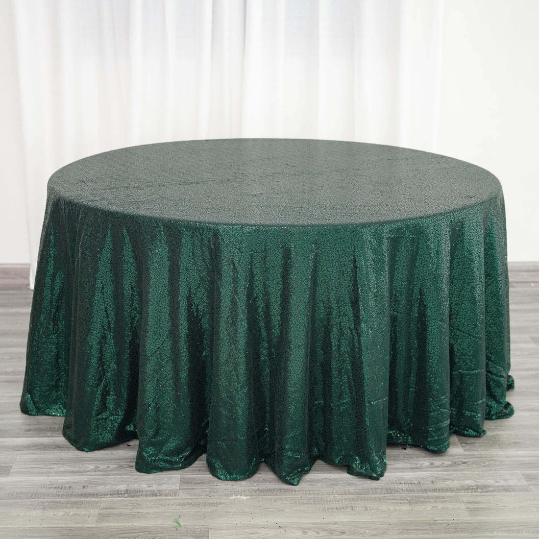 Green sequin tablecloth draping over a round table in a studio setting.