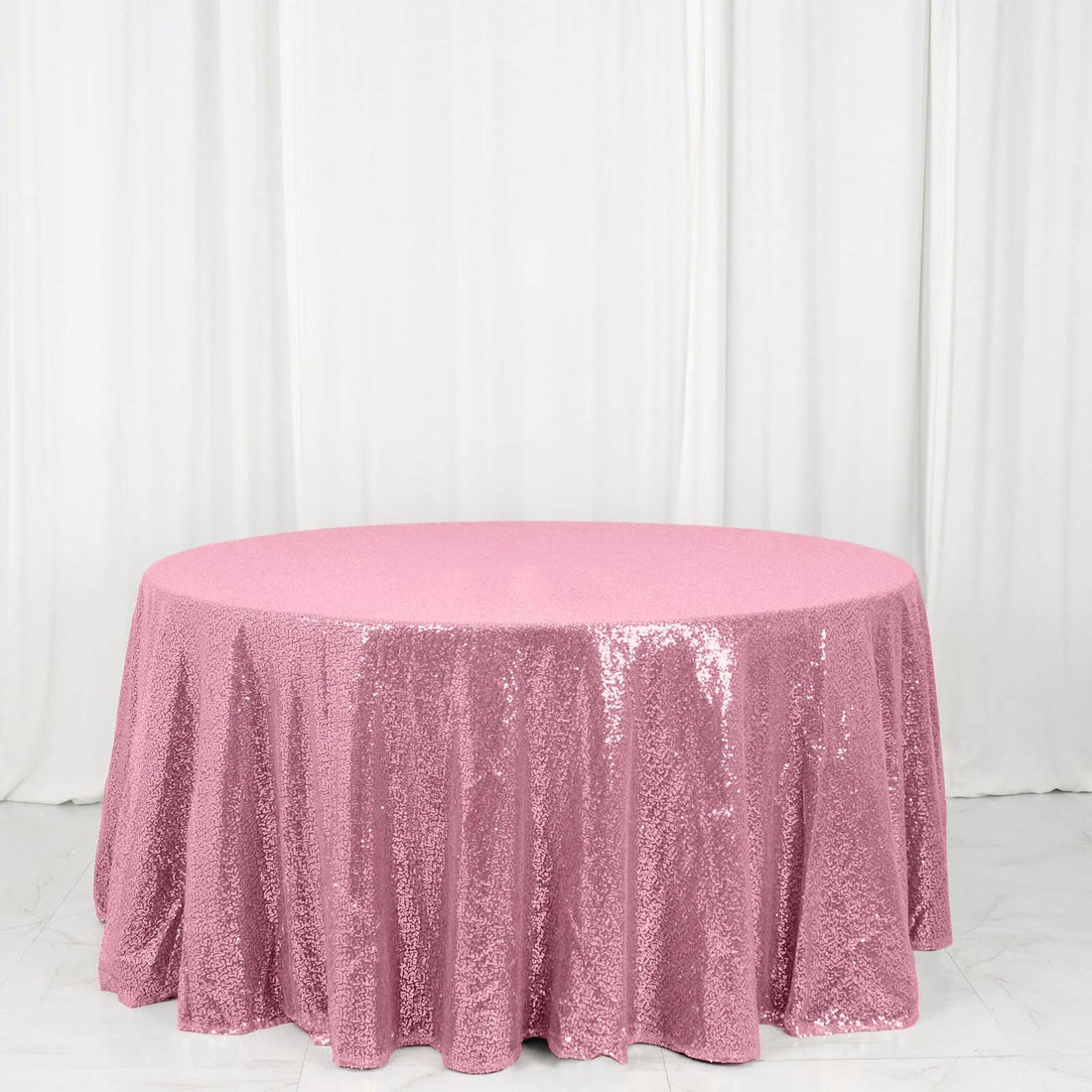 Pink sequin tablecloth on a round table against a white backdrop