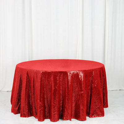 Red sequin tablecloth on a round table against a white backdrop.