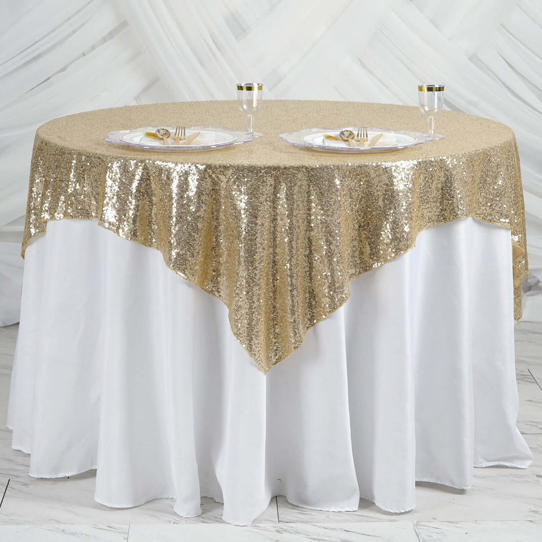 Gold sequin tablecloth draped over a round table set for dining.