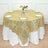 Gold sequin tablecloth draped over a round table with white plates.