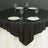 Black tablecloth on a round table set with plates and glassware.