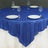 Round blue sequin tablecloth on a dining table with plates and glasses.