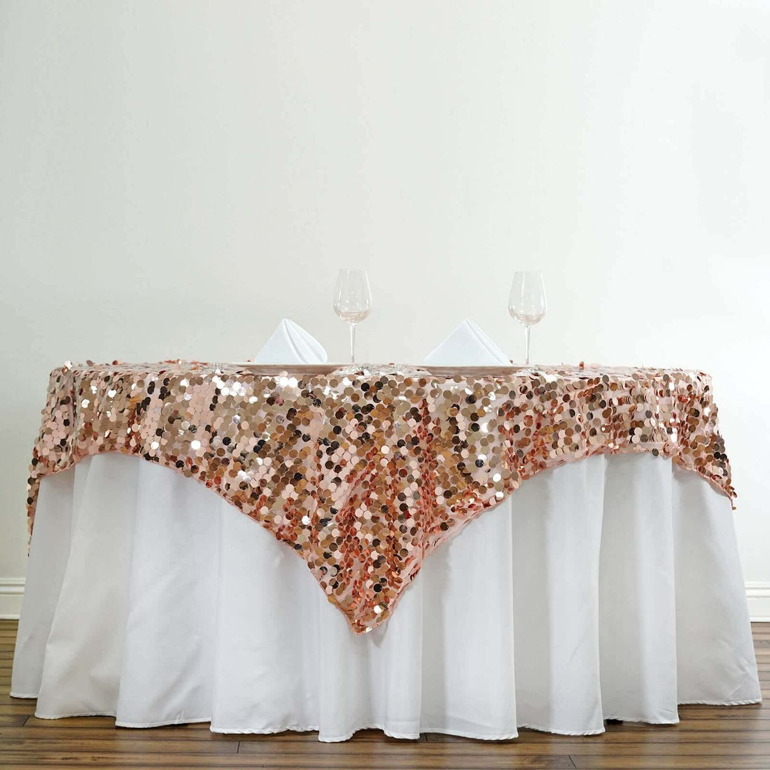 Rose gold sequin tablecloth draped elegantly over a white table.
