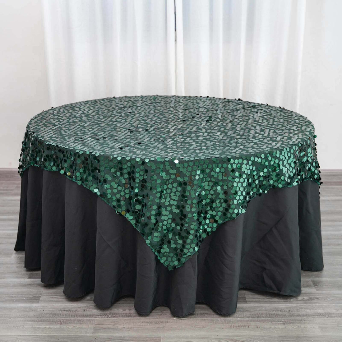Green sequin tablecloth draped over a round table.