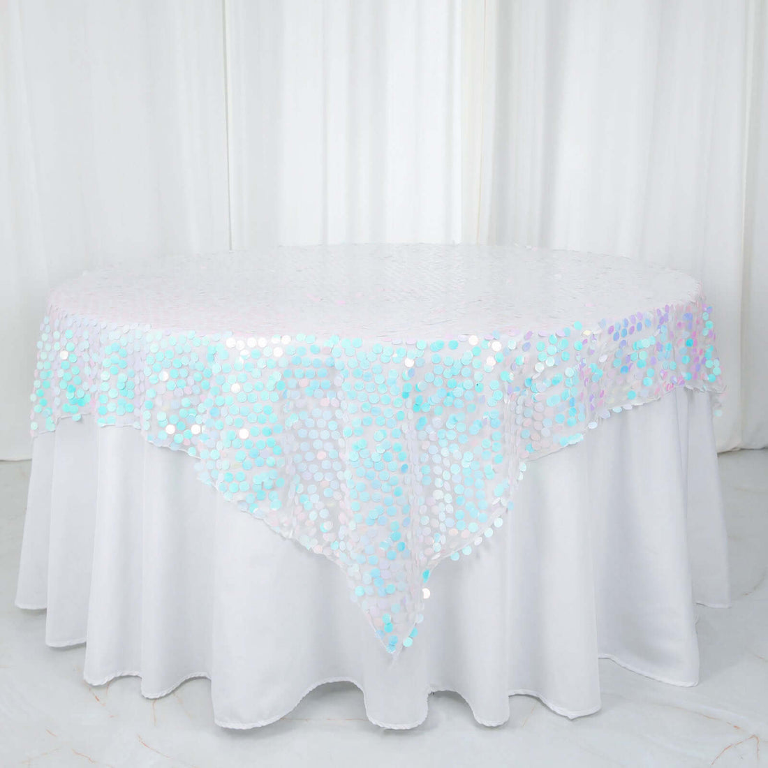Round table covered with a shimmering iridescent sequin tablecloth.