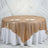 Gold sequin tablecloth draped over a round table with plates and glasses.