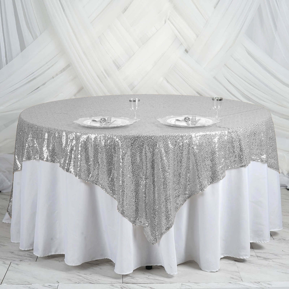 Round silver sequin tablecloth draped elegantly over a white table.