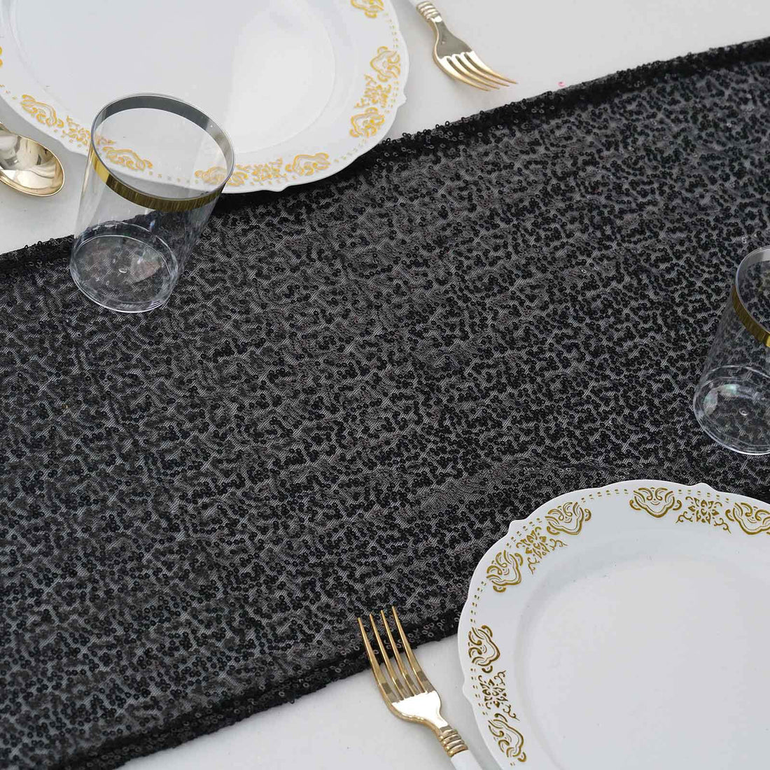 Elegant black table runner with gold detailing, styled with fine dishware.
