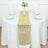Gold geometric table runner on a white table setting with plates and glasses.